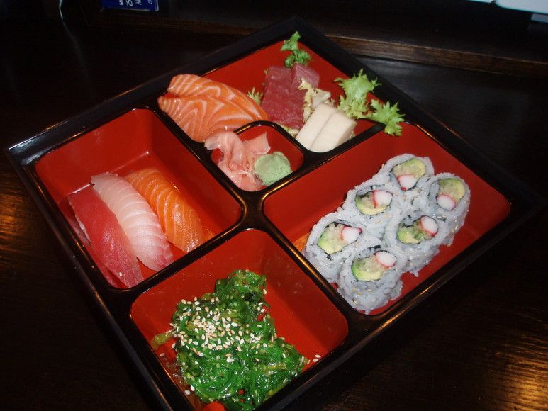 Sushi box with sashimi, California roll and seaweed salad
